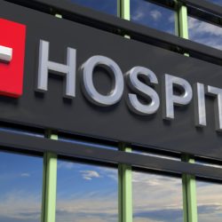 Photo of a Hospital building sign over windows with sky reflecting in the glass