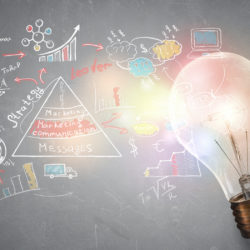Brightly lit light bulb in front of a chalk board with multi colored business planning illustrations