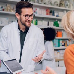 Male pharmacist talking to a female patient at retail health clinic | Vanguard Comm. | Denver, New Orleans