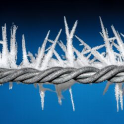 barbed wire in blue background blog illustrates maintaining boundaries on social media and cell phone | Denver, CO | Vanguard Communications