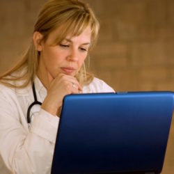 Photo of a woman doctor writing a blog on her laptop