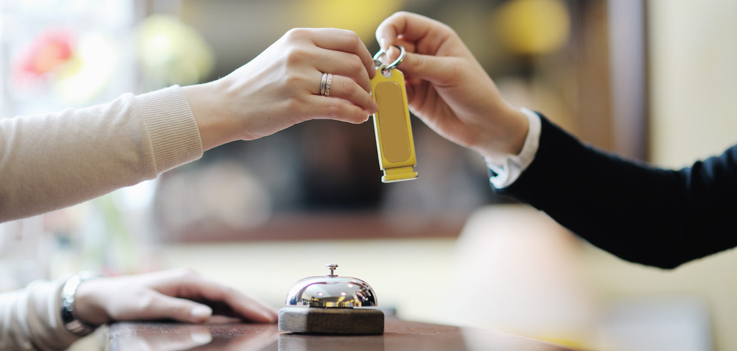 Hotel receptionist giving a guest her room key, a lesson from the hospitality industry on healthcare customer service | Vanguard Communications | Denver